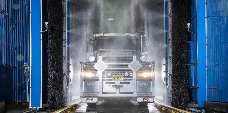 Mack truck front-on in the Hills Truck Wash bay with water spraying